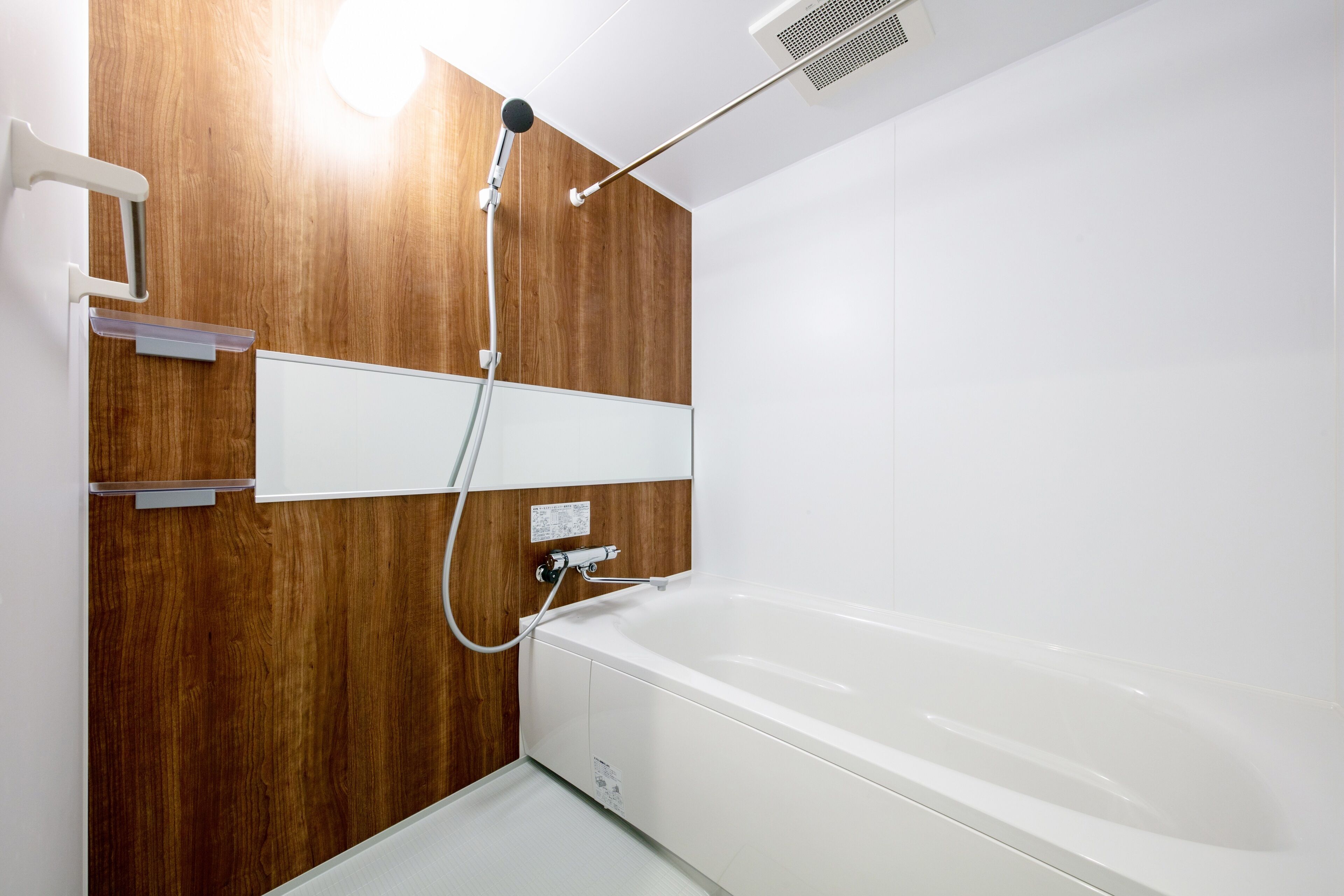 Une salle de bain moderne avec un mur en bois, une baignoire blanche et une pomme de douche.