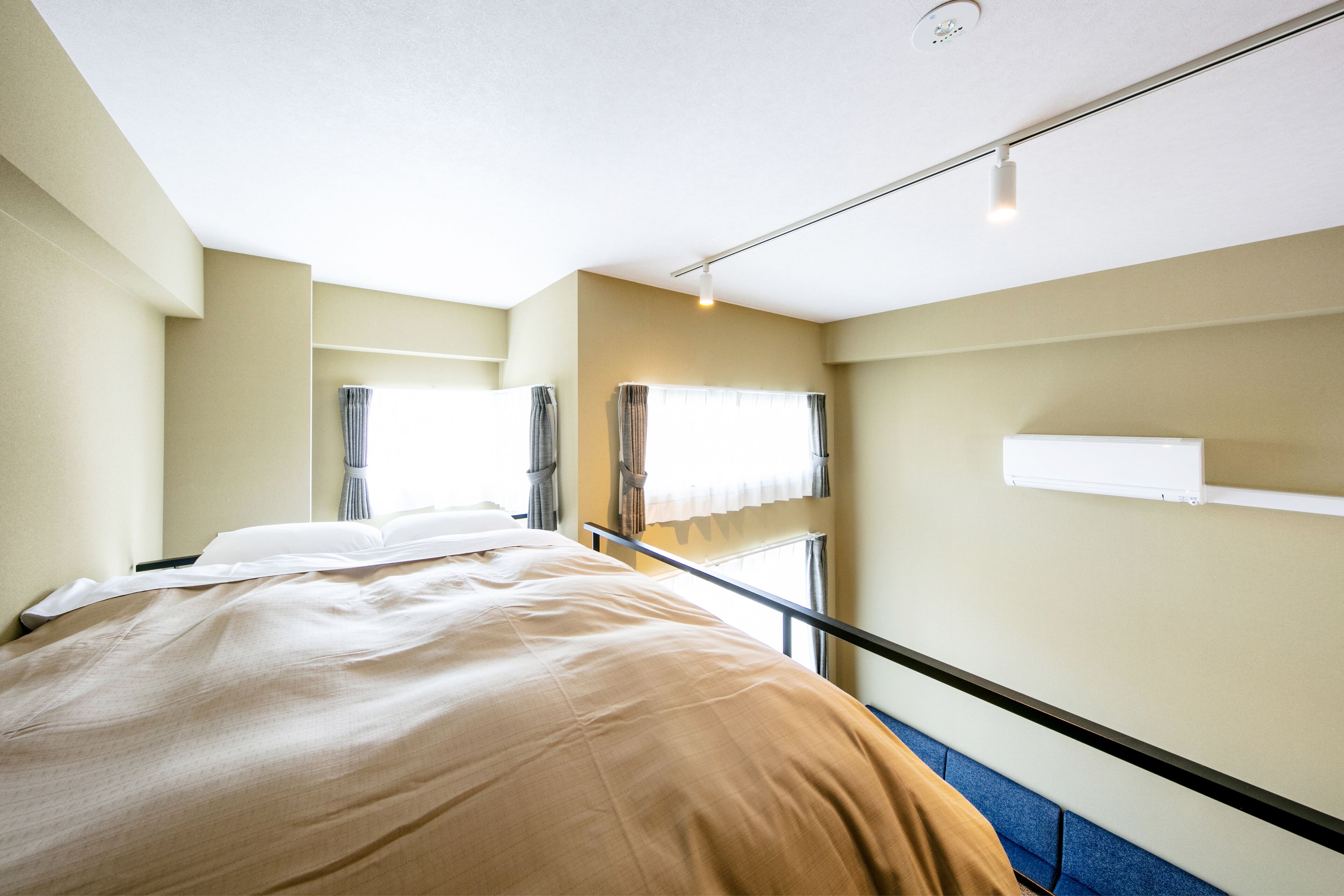 Una habitación de hotel con una cama, una ventana con cortinas, una mesita de noche y un estante en la pared.