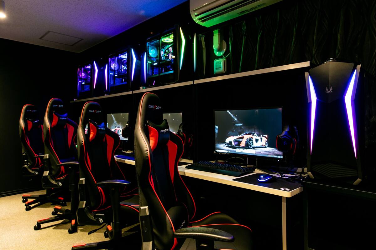 A gaming setup with multiple chairs, a desk, and computer monitors displaying a racing game.