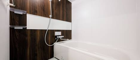 A modern bathroom with a wooden accent wall, a white bathtub, and a showerhead.