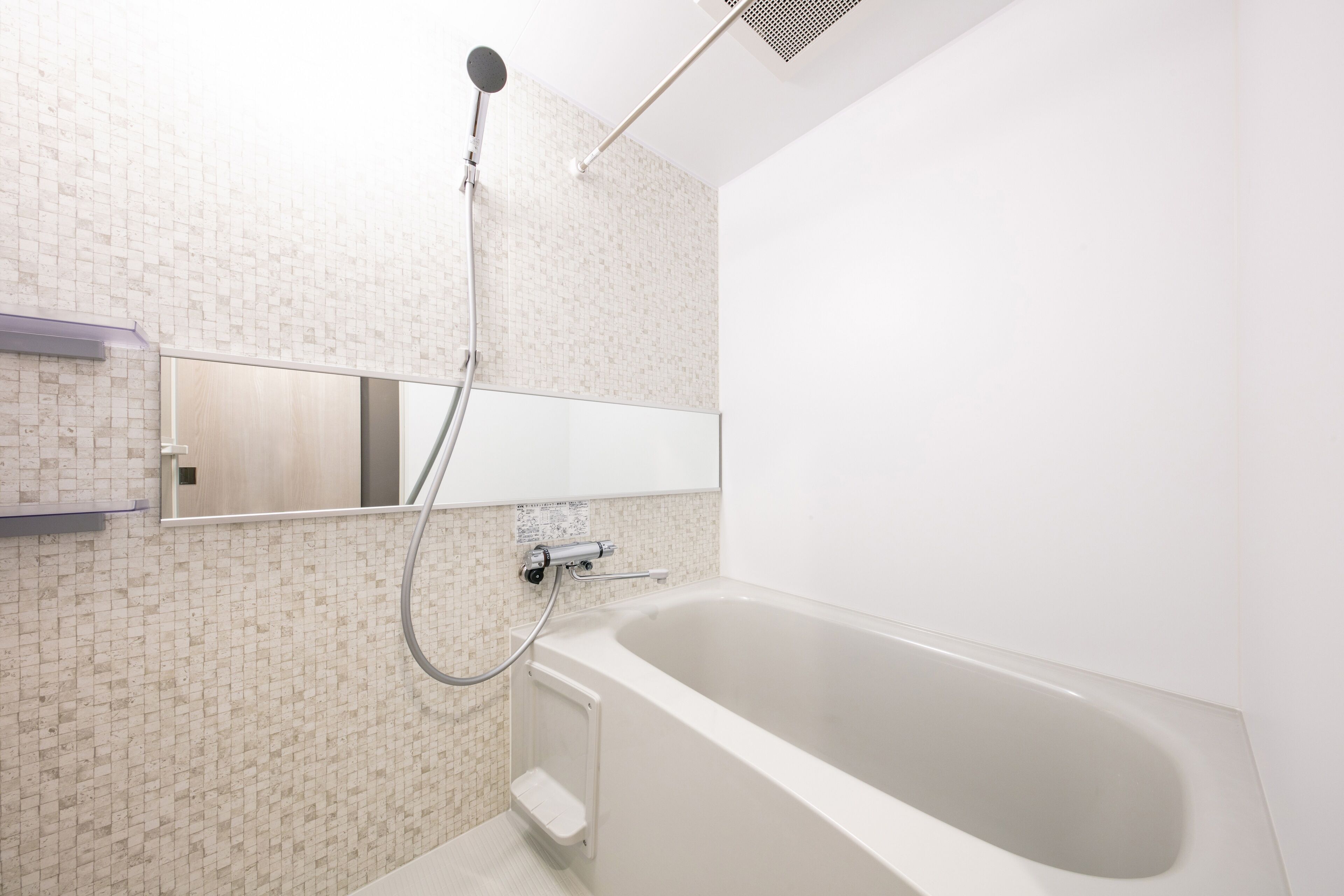 Un baño moderno con una bañera independiente, un cabezal de ducha manual y un espejo instalado en la pared.