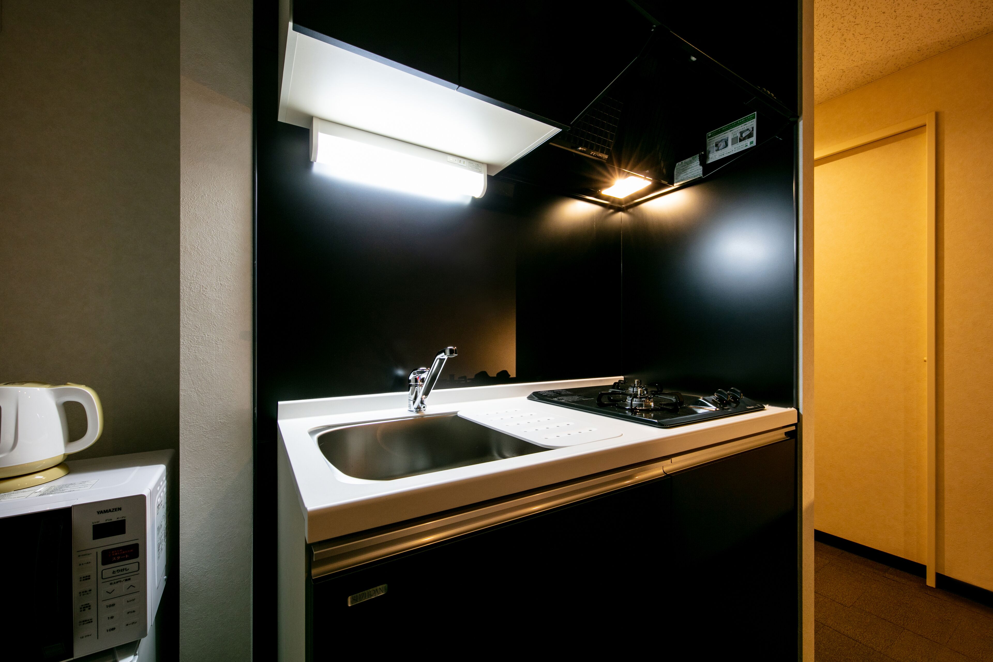 A compact kitchen with a microwave, sink, and stove.