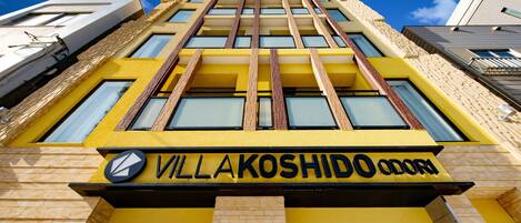 A building with a yellow facade and the name "VILLAKOSHIDO ODORA" prominently displayed.