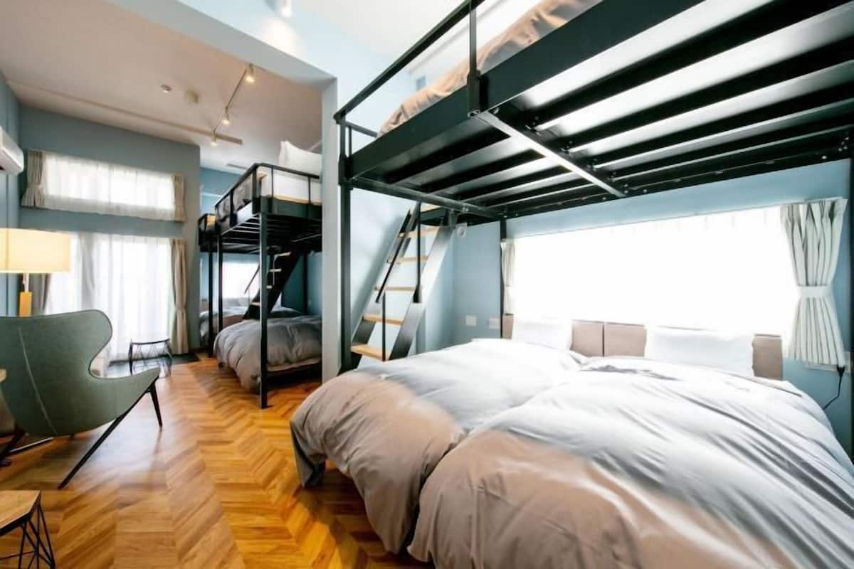 A bunk bed room with a desk and chair, a lamp, and a window with curtains.