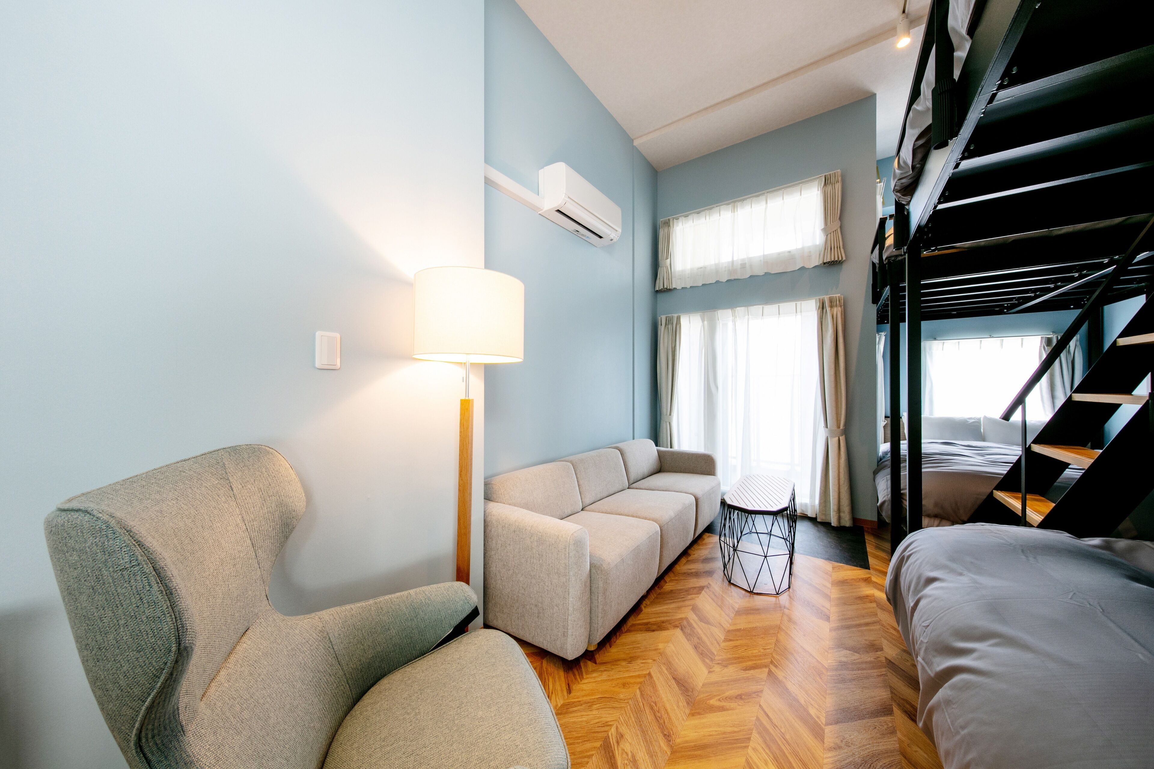 Una sala moderna con un sofá, una silla, una lámpara y una cama litera.