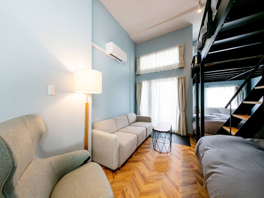 Una sala moderna con un sofá, una silla, una lámpara y una cama litera.