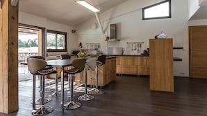 A modern kitchen with wooden cabinets, a central island, and bar stools. - E case di u Puntale, Villa with swimming pool ideal for family vacations. (Ghisonaccia)