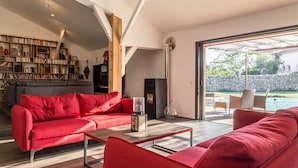 A modern living room with a red sofa, a coffee table, and a bookshelf filled with books. - E case di u Puntale, Villa with swimming pool ideal for family vacations. (Ghisonaccia)