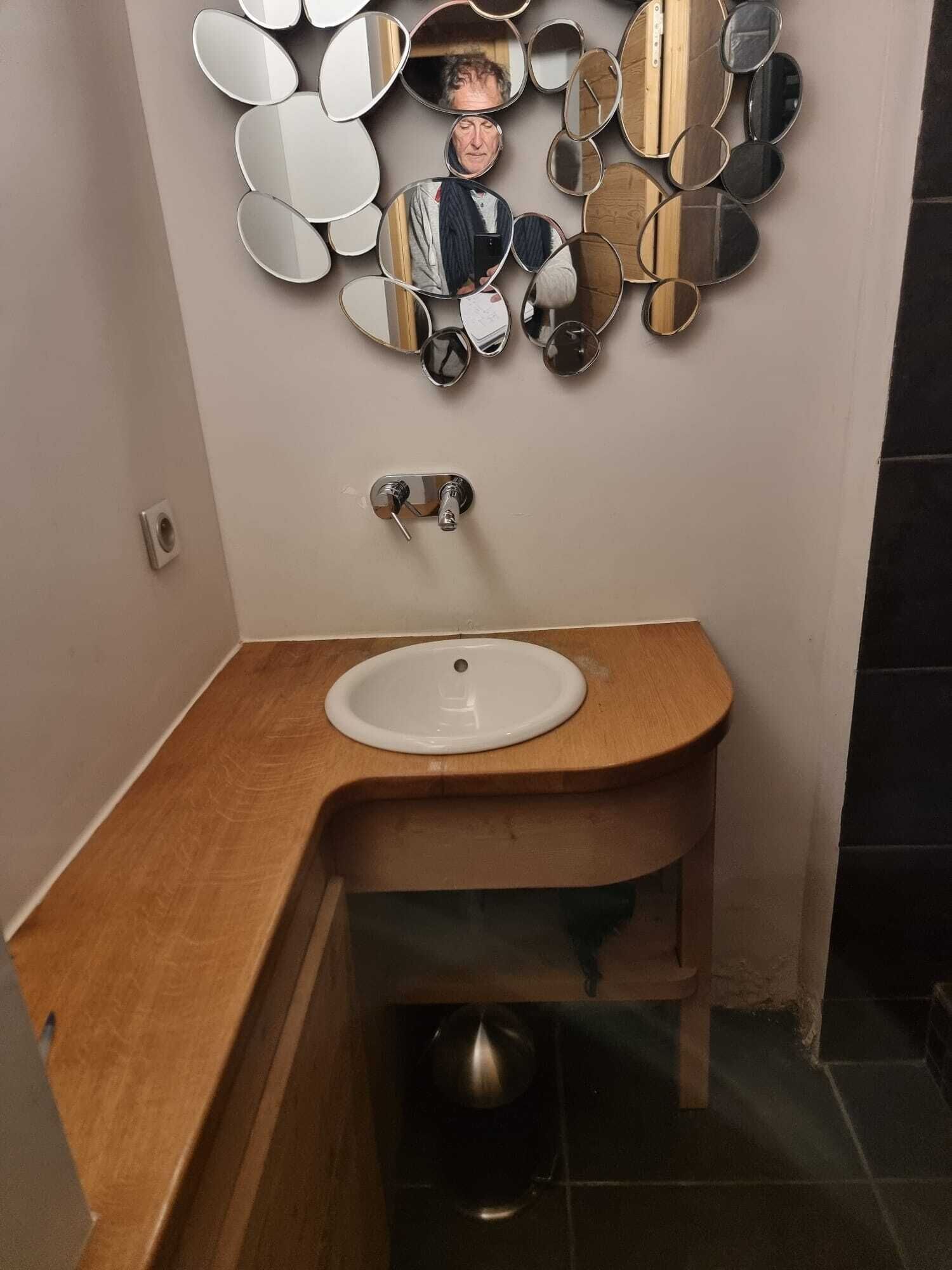 Un bagno con un mobile vanitario in legno, un lavandino bianco e uno specchio montato a parete.