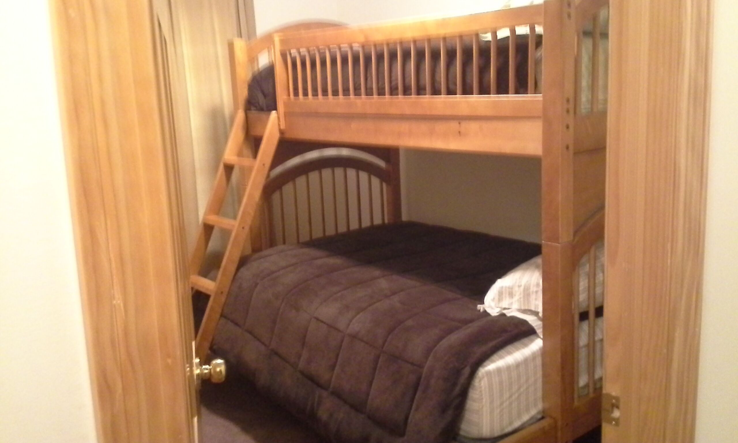 Ein Stockbett mit Holzlade und Kopfstütze.