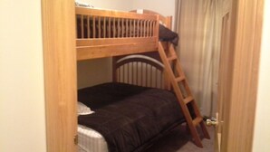 Ein kleines Zimmer mit einem Holzbett und einer Himmelsleiter.