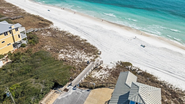 Una spiaggia con una passerella in legno che conduce a un edificio con tetto spiovente.