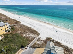 A beach with a wooden boardwalk leading to a building with a sloped roof. - Delightful coastal escape located steps to the pool & 350 yards to beach access (Inlet Beach)