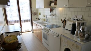 A kitchen with white cabinets, a sink, a stove, a dishwasher, and a washing machine.