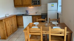 Eine kompakte Küche mit Holzausstattung, einer Mikrowelle, einem Kühlschrank, einer Spüle und einem Esstisch mit Stühlen.