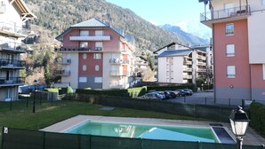 A residential area with multi-story buildings, a swimming pool, and a mountainous backdrop.