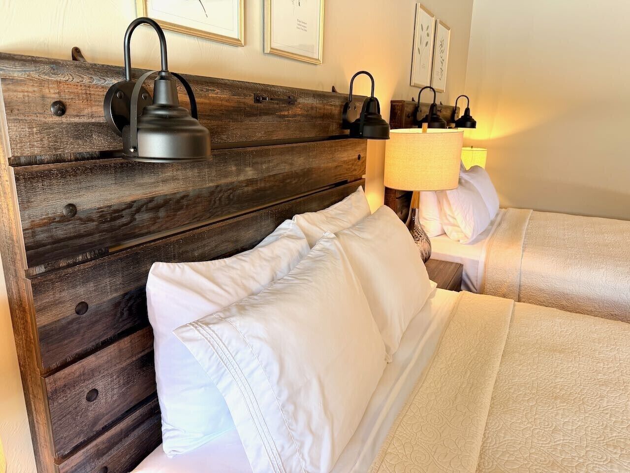 A bed with white linens, a wooden headboard, and two bedside lamps.