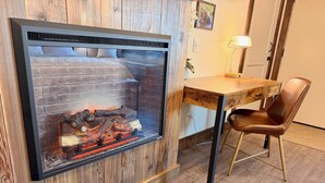 A room with a fireplace, a wooden desk, a chair, and a lamp. - Arrowhead Properties Unit 6 (West Yellowstone)