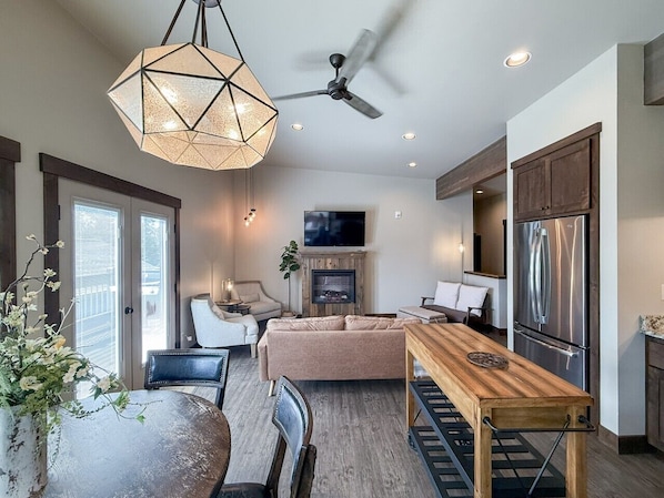 A modern kitchen with a built-in refrigerator, a dining table with chairs, and a ceiling fan.