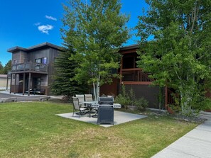 A modern outdoor patio with a grill, seating, and a small table.