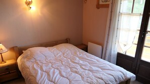 Une chambre à coucher avec un lit en bois, une table de chevet avec une lampe et une fenêtre avec des rideaux.