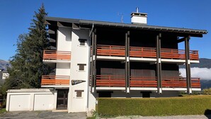 Un bâtiment moderne à deux étages, doté de balcons, d’un garage et offrant une vue dégagée sur le paysage environnant.