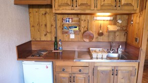 Une cuisine compacte avec des meubles en bois, un évier encastré et un petit réfrigérateur.