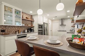 A modern kitchen with a central island, white cabinetry, and a brick backsplash. - The Great Escape! Modern, Secluded Retreat, Views! (Sedona)