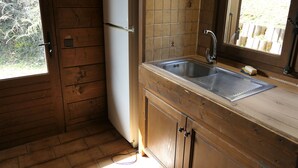 Une cuisine compacte dotée de meubles en bois, d’un évier en acier inoxydable et d’un réfrigérateur encastré.
