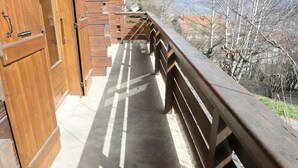 Un balcon en bois avec une balustrade en métal, donnant sur un paysage montagneux.