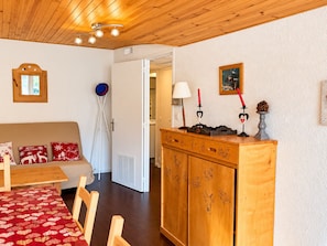 Une pièce chaleureuse avec un plafond en bois, un canapé agrémenté de coussins rouges et blancs, un meuble en bois orné de motifs décoratifs et un miroir au mur.