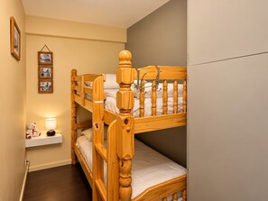Ein Etagenbett mit Nachttisch und Lampe, ein gerahmtes Bild an der Wand und ein Teddybär auf dem Tisch.