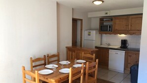 A compact kitchen with wooden cabinets, a microwave, a refrigerator, and a dishwasher.
