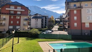 A residential area with apartment buildings, a swimming pool, and a mountain backdrop.