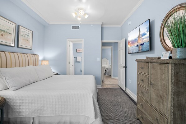A bedroom with a bed, a dresser, a mirror, and a framed picture on the wall.