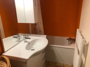 A bathroom with a white sink, mirror, and bathtub. - Studio for 4 with balcony near shuttle (Saint-Gervais-les-Bains)