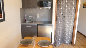 Una cocina compacta con microondas, fregadero y un refrigerador pequeño.