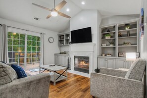 A living room with a fireplace, television, and a view of the outdoors through a sliding glass door.