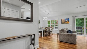 A spacious living area with a dining table, a gray sofa, and a large mirror. - Sleeps 12 in  Innsbruck cabin near downtown Helen. (Helen)