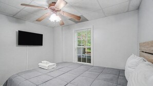 A bedroom with a bed, a ceiling fan, a TV, and a window with blinds. - Sleeps 12 in  Innsbruck cabin near downtown Helen. (Helen)