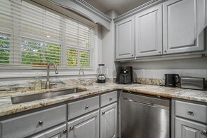 A kitchen with a sink, stove, and cabinets.