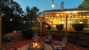 A patio with a fire pit, outdoor seating, and a house with a balcony. - Sleeps 12 in  Innsbruck cabin near downtown Helen. (Helen)