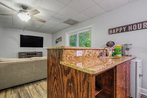 Eine Küche mit Granit Arbeitsplatte, einem Deckenventilator, einem Fernseher und einem Schild mit der Aufschrift 'HAPPY HOUR'.