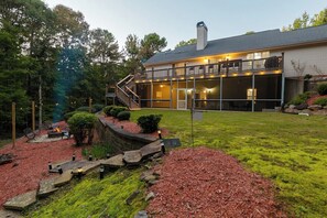 A house with a covered porch, a fire pit, and a landscaped yard with red mulch and green grass.