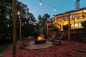 An outdoor patio with a fire pit, seating, and string lights.