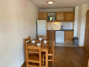 A compact kitchen with wooden cabinets, a microwave, and a dishwasher.
