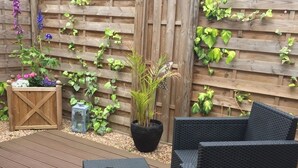An outdoor patio with wicker furniture and a wooden fence. - THE DOLCE VITA SUITE (Sin-le-Noble)