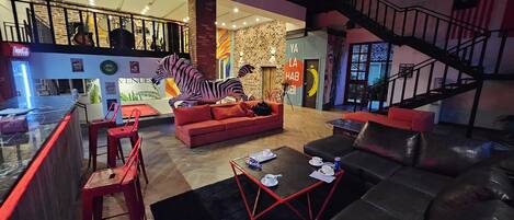A spacious lounge area with a zebra sculpture, red seating, and a staircase.