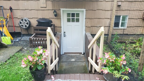 A front view of a house with a white door, a small front yard, and a wooden fence. - Private and spacious apartment close to Cornell in quiet residential area. (Ithaca)
