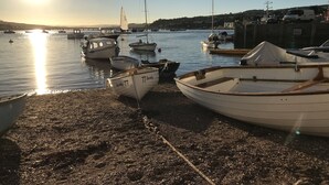 En hamn med båtar förtöjda längs stranden, en klar himmel och en bro i fjärran.
